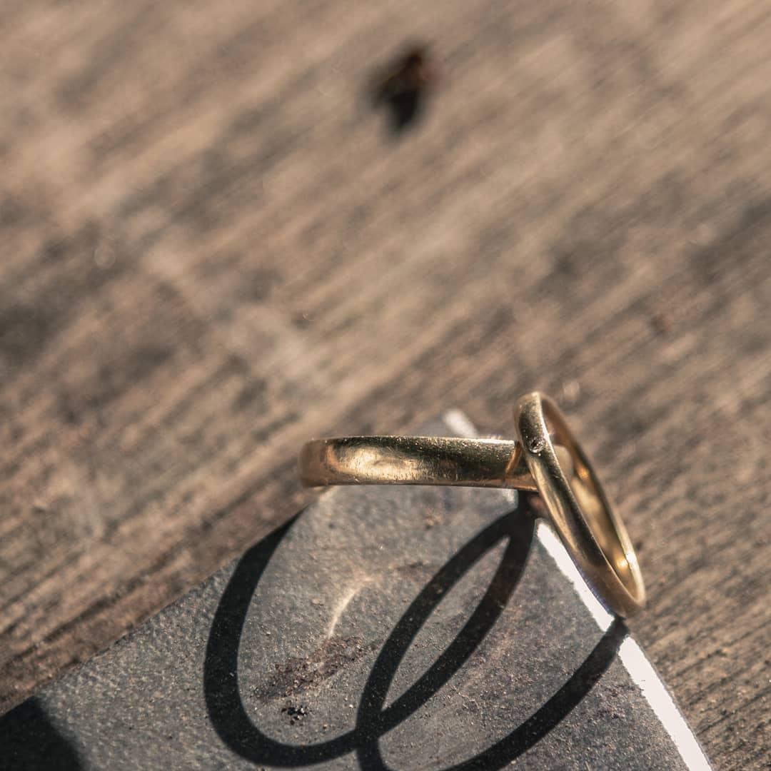 A gold ring lies on a gray surface.  The soft lighting gives a warm and inviting feel.