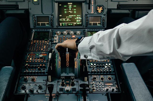 A pilot adjusts the throttle in a modern airplane cockpit, showcasing aviation technology and expertise.