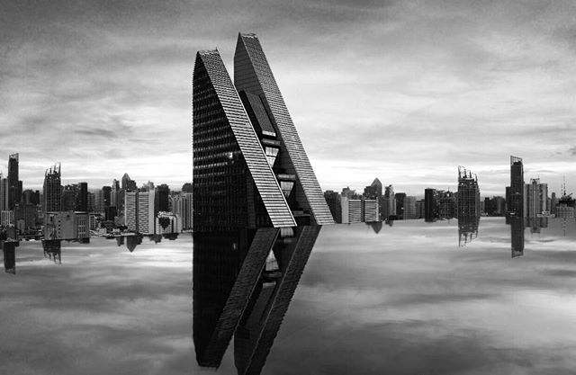 A striking monochrome image featuring modern skyscrapers mirrored in a reflective surface, set against a city skyline.