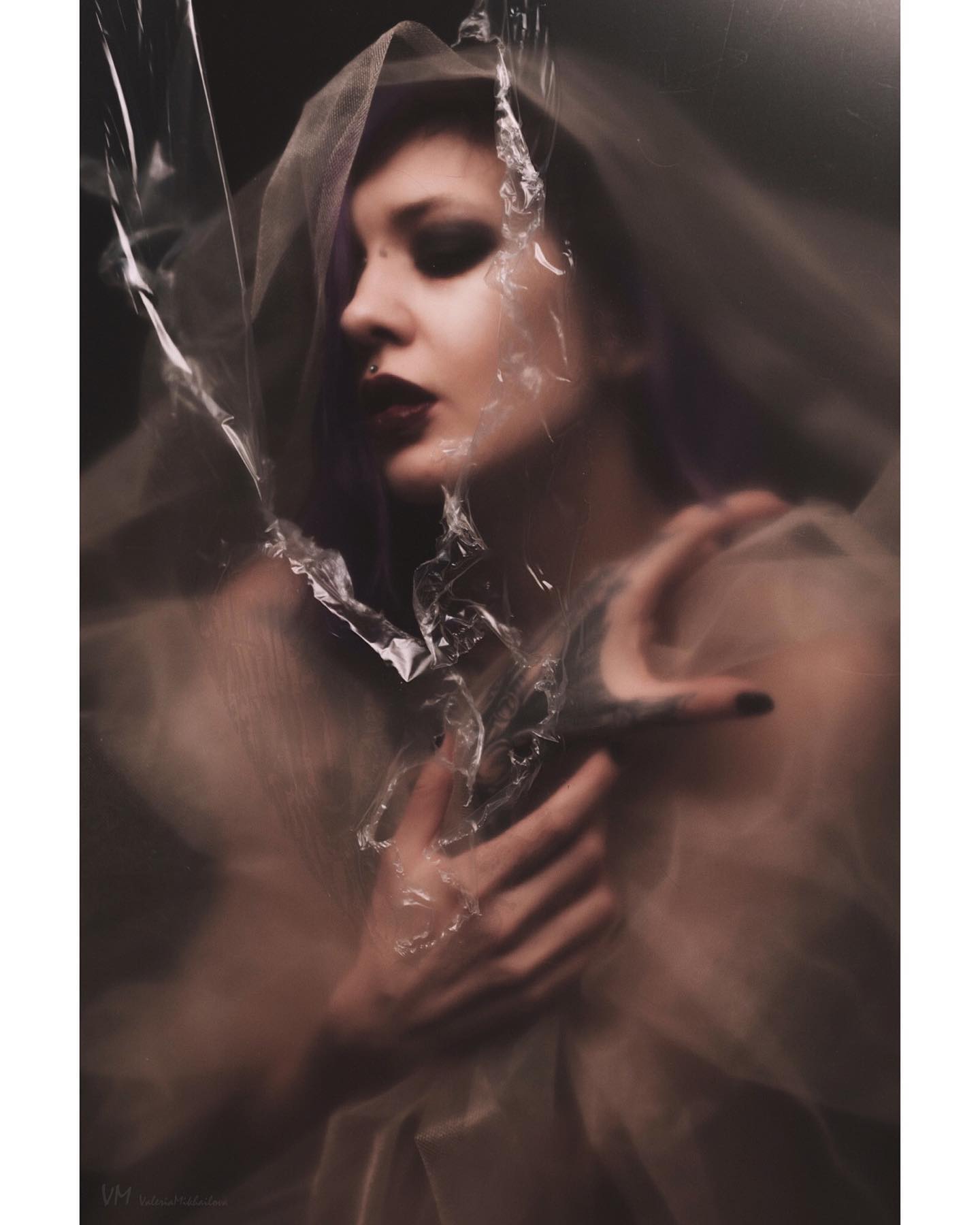 A woman with purple hair is featured in an artistic portrait with a veil, creating a moody and surreal atmosphere.