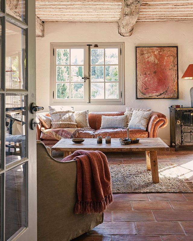 Cozy living room featuring a rustic coffee table, leather sofa, and soft, natural lighting.