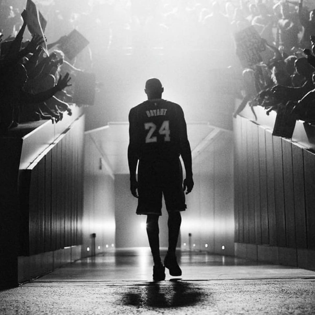 Kobe Bryant walks through a tunnel of fans in a black and white, low angle silhouette.