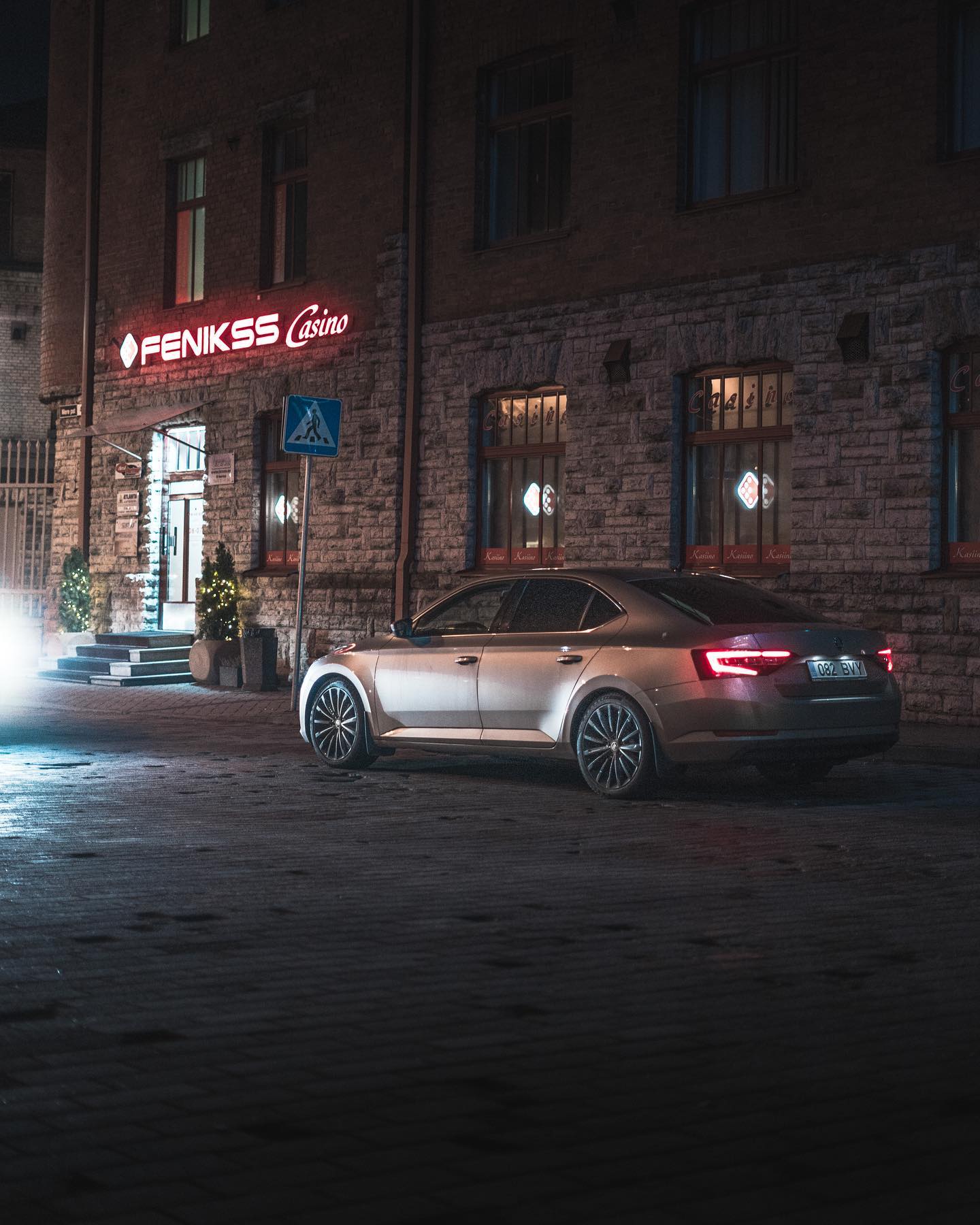 An elegant car is parked outside a brightly lit casino at night, inviting visitors for an evening of entertainment.