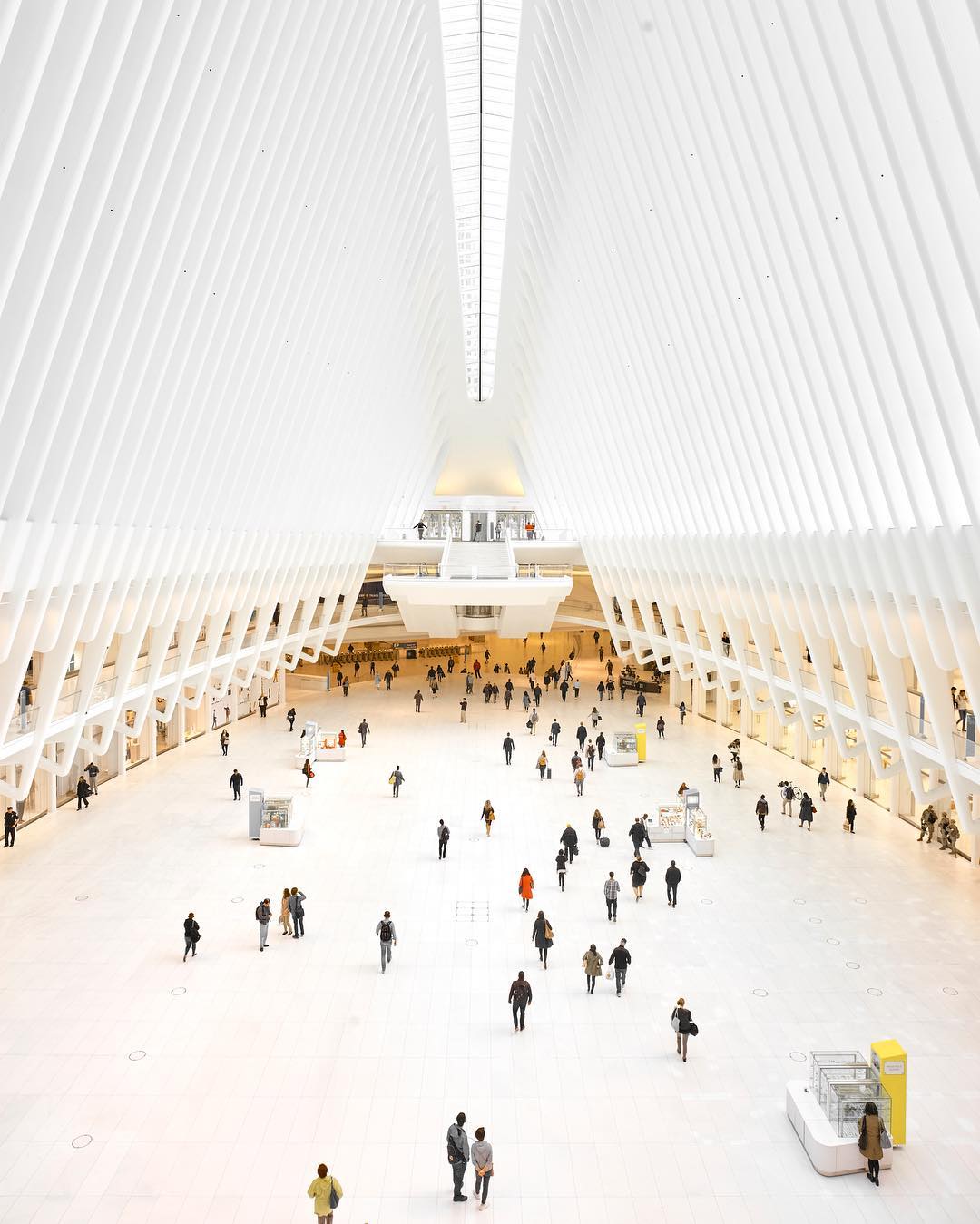 Interior of a modern transportation hub, featuring a bright, spacious hall filled with people moving about.