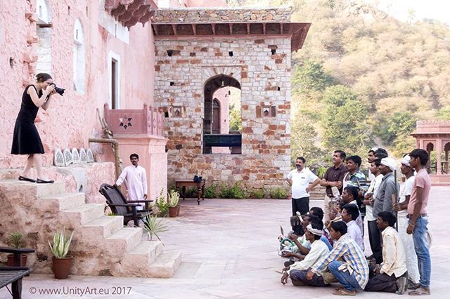 A photographer takes photos of a group of people in the courtyard of an old building.
