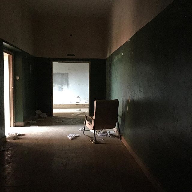 An old chair sits in a dim hallway of an abandoned building, hinting at a forgotten past and a sense of mystery.