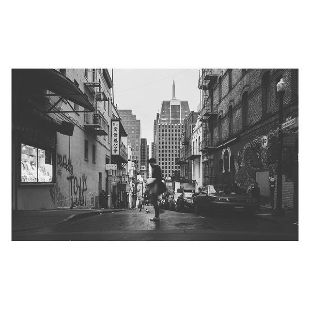 A grayscale street scene showcases a person walking on a city street with tall buildings in the background.
