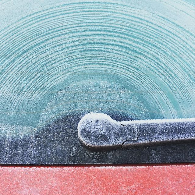 Frosty windshield with wiper on a cold winter morning creates a serene, minimalist scene.