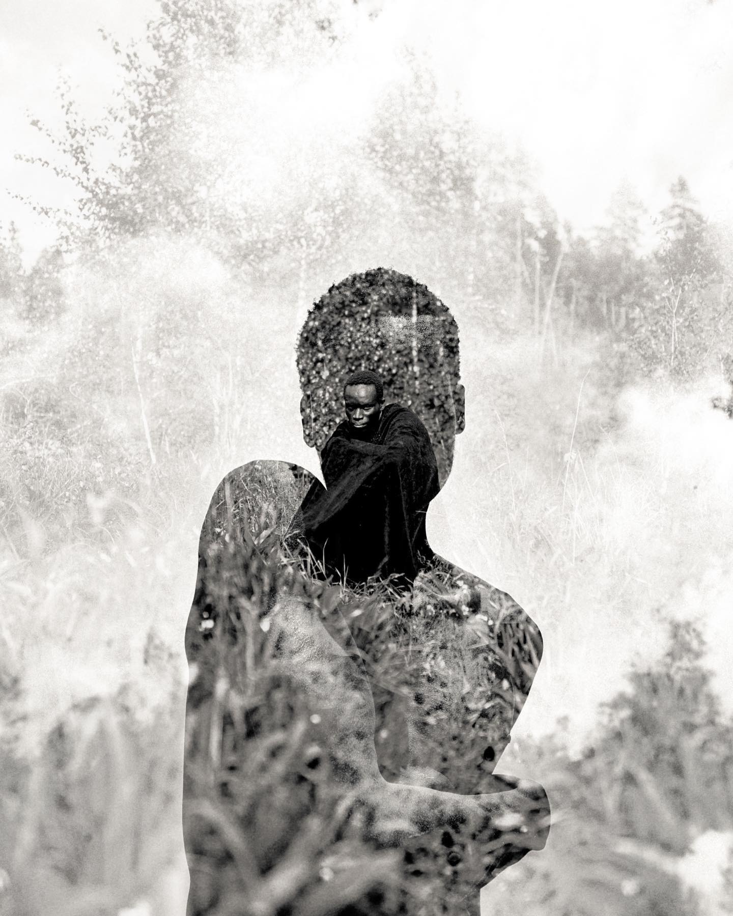 A monochrome double exposure of a man merging with a forest landscape, creating a serene and contemplative portrait.