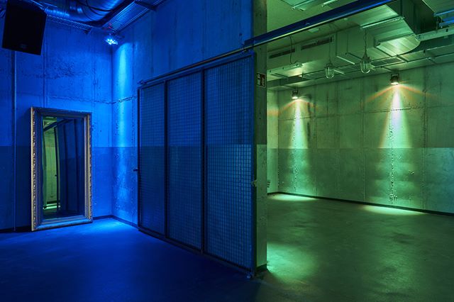 A modern warehouse room interior with blue and green lighting. A versatile empty space.