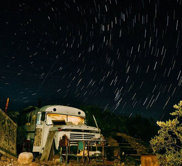 An old bus sits under a star-filled night sky captured in a long exposure for a dreamy effect.