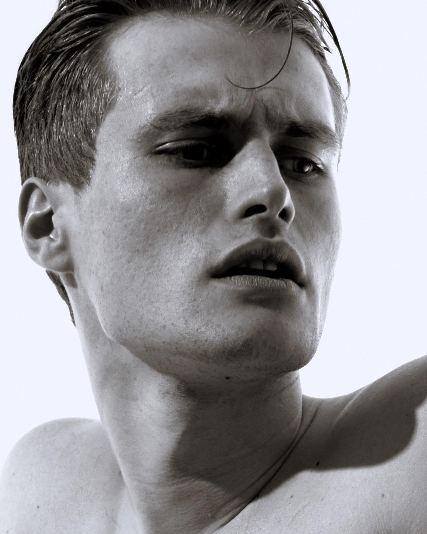 A striking black and white portrait of a man with intense gaze, shot in studio for editorial or advertising use.