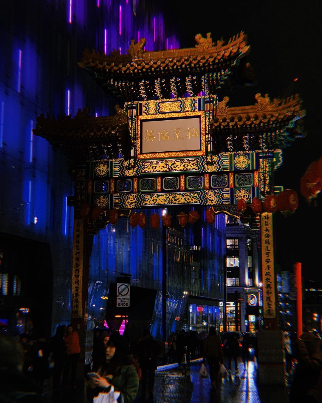 A vibrant scene of London's Chinatown at night, showcasing the gate and bustling crowds.