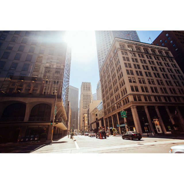 A sunny urban scene featuring tall buildings and cars on a city street. Ideal for travel and urban lifestyle content.