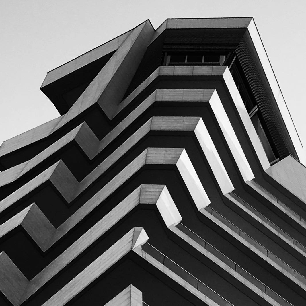 Abstract black and white view of a modern building's geometric facade. High contrast and sharp architectural lines.