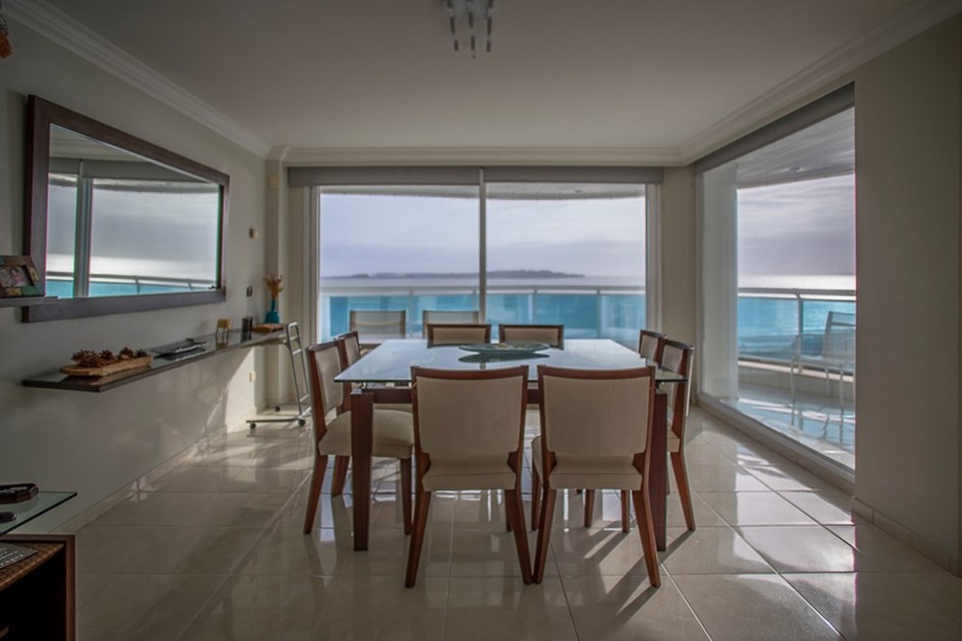 A bright and airy dining room with a modern glass table and neutral-toned chairs offers a serene and stylish living space.