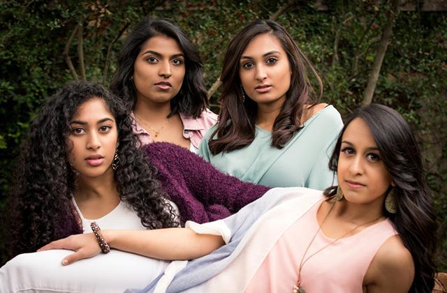 Four young Indian women pose together outdoors, exuding confidence and friendship in a natural setting.