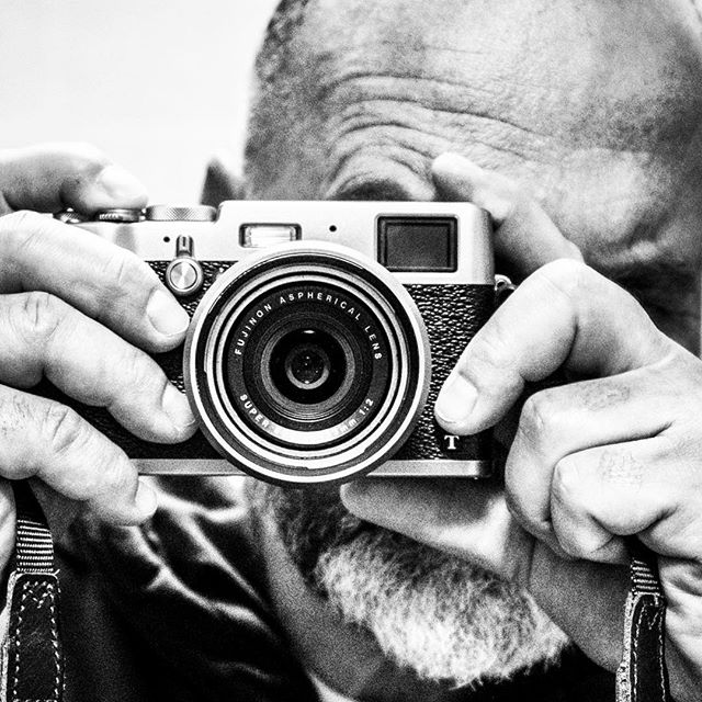 A photographer focuses using a vintage camera in a black and white portrait.