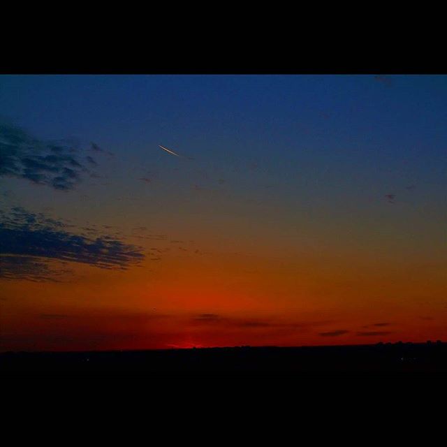 A vibrant sunset paints the sky with warm colors over a tranquil horizon, creating a peaceful landscape at dusk.