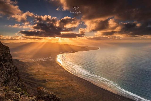 A serene beach scene at sunset with golden light streaking through the clouds, perfect for travel and tourism.