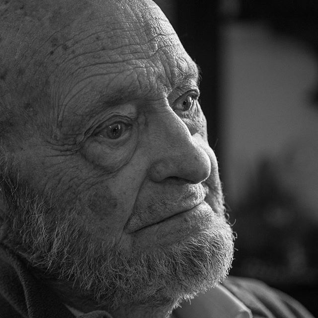 A black and white portrait of an elderly man's face shows age and character in sharp detail.