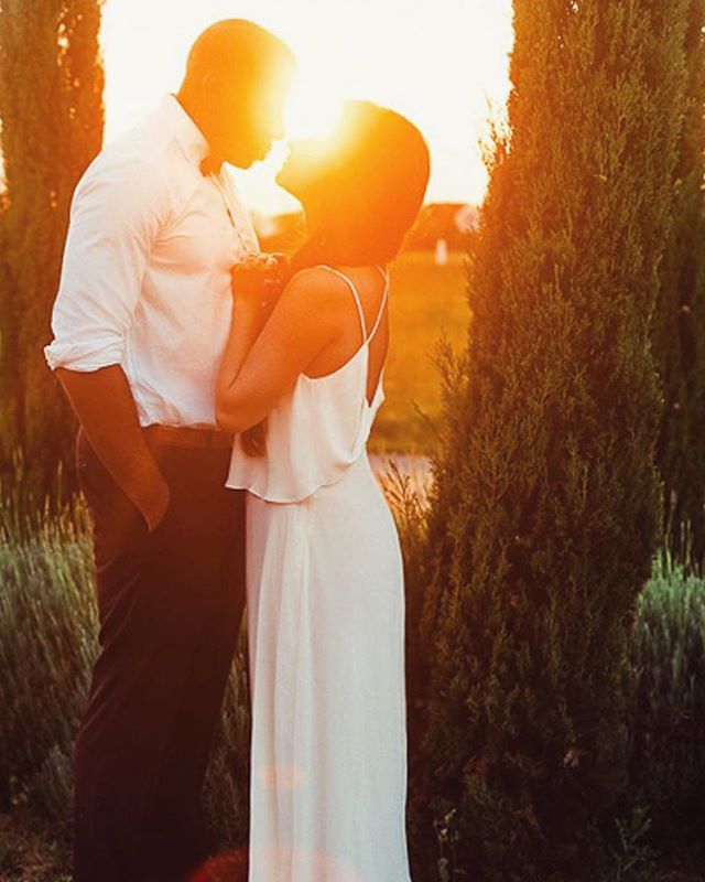 A couple embraces at sunset surrounded by nature, radiating warmth and intimacy.
