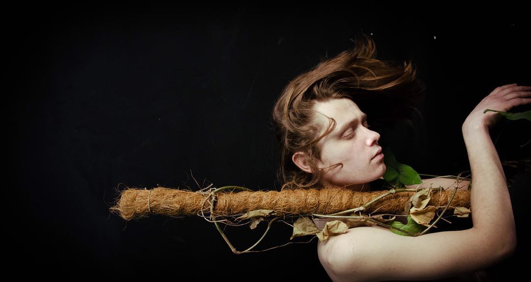 Artistic shot of a man with plants and natural materials, emphasizing wellness and organic themes.
