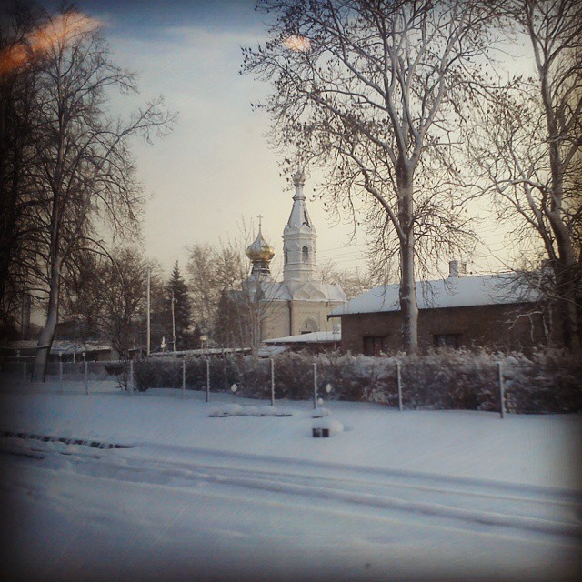 A serene winter scene with a church in the background covered in snow.