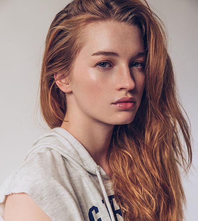 Portrait of a young redhead woman in a studio with soft, natural lighting.