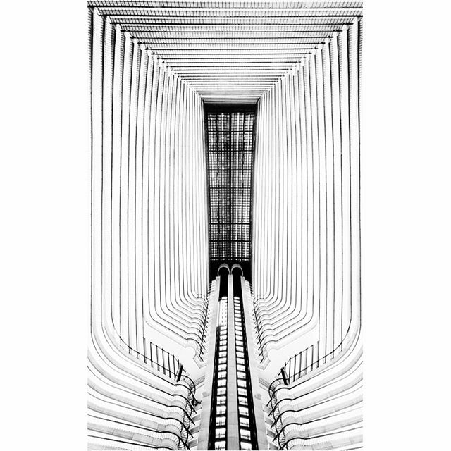 Abstract black and white architecture shot featuring escalators in a modern building atrium.