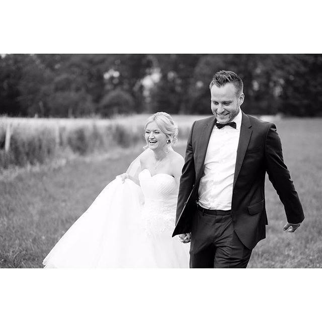 A bride and groom share a happy moment walking in a field on their wedding day.