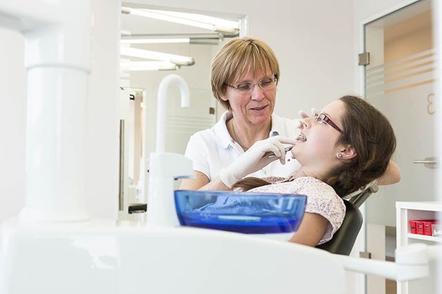 A dentist examines a young patient's braces in a bright dental office, ensuring proper orthodontic care and alignment.