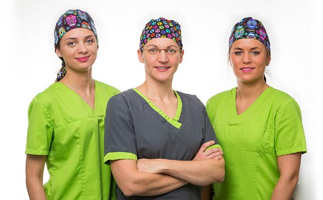 Three healthcare professionals in scrubs and caps stand against a white backdrop.