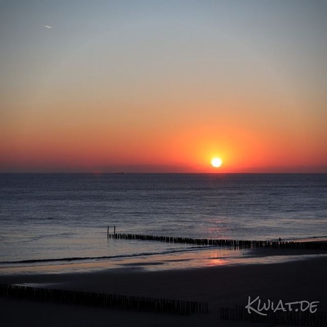 A vibrant sunset over the ocean creates a tranquil and serene beach scene, perfect for travel and relaxation.