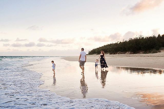 A family walks on a sandy beach at sunset, enjoying the ocean and a peaceful vacation.