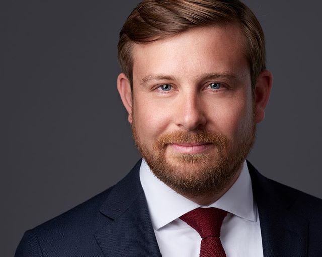 Professional headshot of a confident man in a suit and tie, suitable for corporate branding.