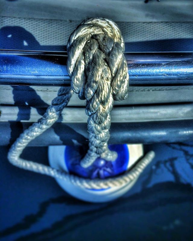 A close-up captures a knotted rope secured to a boat, highlighting maritime detail and calm waters.