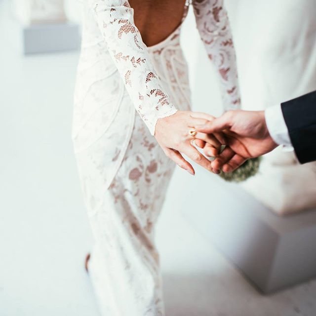 A bride and groom hold hands, showcasing a wedding ring during an intimate wedding moment.
