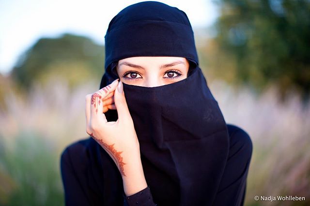 A woman in a niqab gazes intensely at the camera, highlighting her expressive eyes.