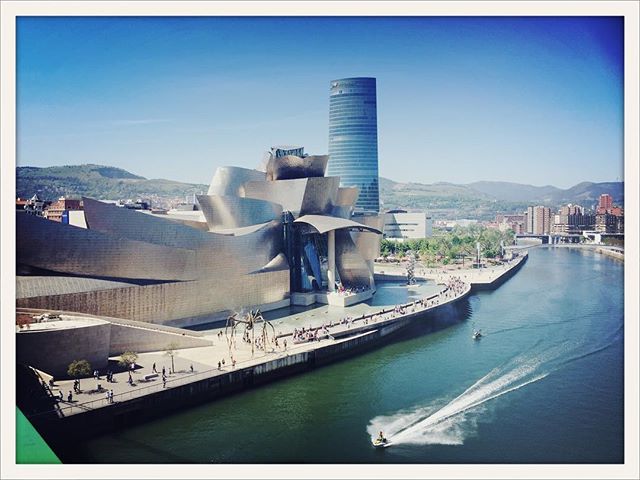 View of the Guggenheim Museum and Iberdrola Tower in Bilbao, Spain, with jet ski on the Nervion River.