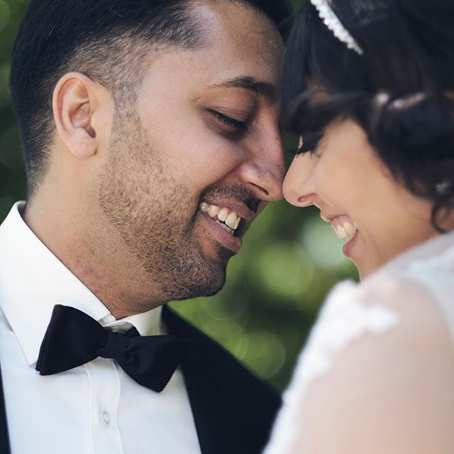 A smiling bride and groom lovingly nuzzle noses on their wedding day, creating an intimate and romantic moment.