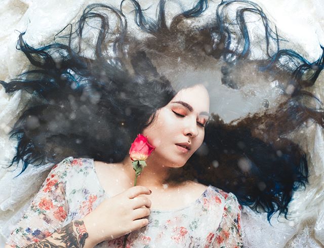 A serene woman lies with eyes closed, holding a rose, a dreamy image for wellness and beauty campaigns.