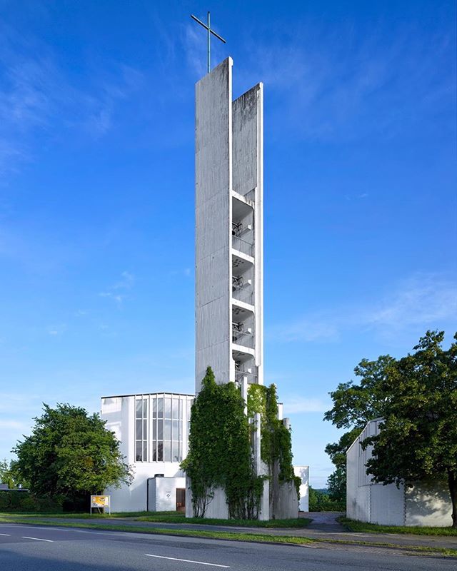 A striking view of a modern church tower against a blue sky, symbolizing faith and architectural design.