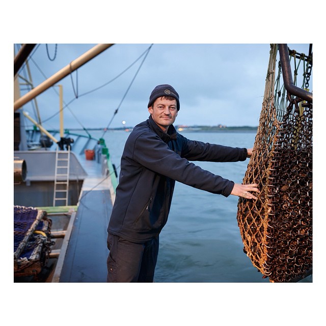 A fisherman holds a net on a boat at sea, showcasing the maritime industry and sustainable fishing practices.