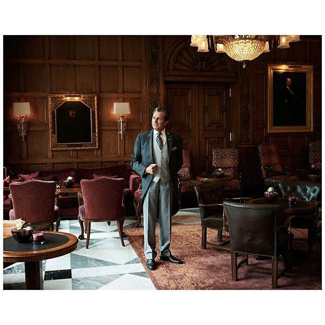 An elegant man in a tuxedo stands in a luxurious hotel lobby, radiating sophistication and class.