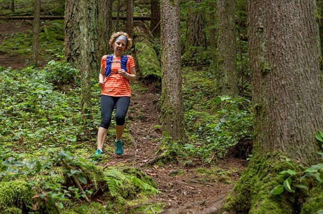 A woman trail runs through a lush forest, showcasing an active and healthy outdoor lifestyle.