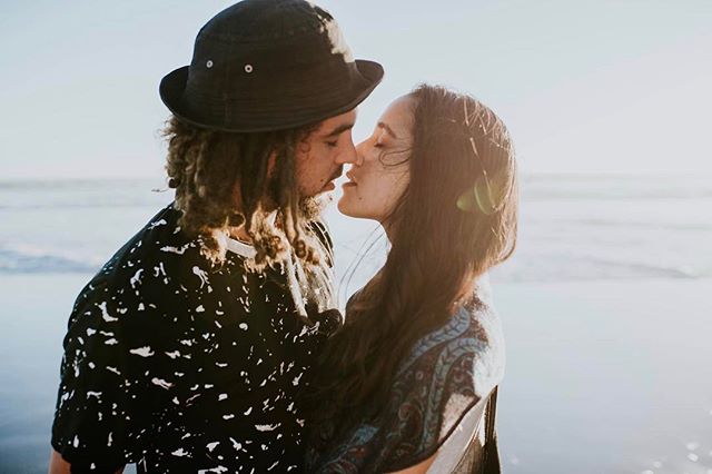 A loving couple shares a tender moment on the beach at sunset, bathed in soft, warm light.