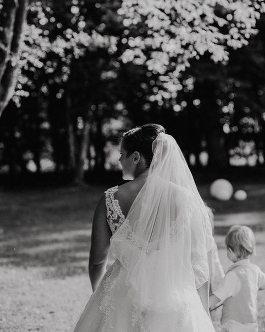 A bride walks with a child in an elegant wedding dress and veil.