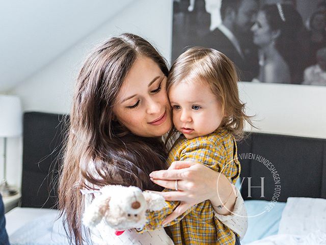 A mother lovingly embraces her young child in a tender, intimate moment indoors.