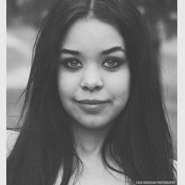 A serene black and white portrait of a woman with long dark hair, captured in soft, natural light.